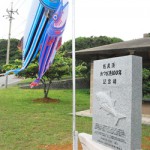 このほど建立された１００周年記念碑とカツオのぼり＝11日、佐良浜漁港