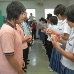 友好の証として折り鶴をプレゼントする生徒ら＝12日、下地中学校