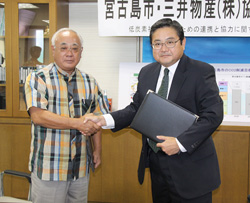 協定を結び握手を交わす下地市長（左）と鈴木プロジェクト本部長補佐＝16日、市長室