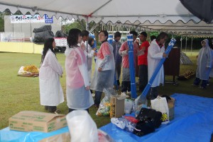 中止が決まり、雨の中撤収作業をする関係者たち＝７日、カママ嶺公園