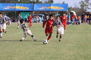 中学年決勝で体を張ってボールを競う平良第一ＳＣと南コンサドーレの選手