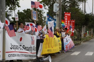 星条旗と日の丸を振って歓迎の意を表す幸福実現党のメンバーら（左）。右隣は米軍機の空港使用に反対する市民団体ら＝11日、宮古空港前