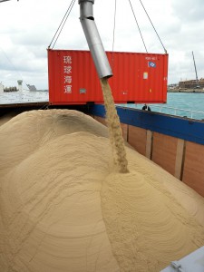 宮糖城辺工場の初荷となる粗糖が船倉に流し込まれた＝15日、平良港