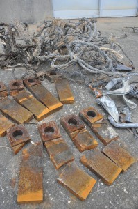 キビ束の中に混入されていた金属類。手前は金属を巻き込んで破壊された工場の機具＝22日、宮糖城辺工場