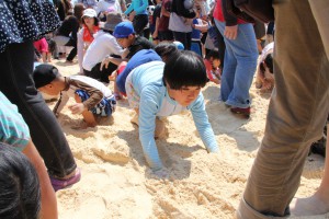 トレジャーハンティングで砂に埋められたカードを探す子どもたち