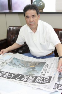 東日本大震災を報じる地元の新聞を手に当時の様子を語る菅浪さん＝９日、本社