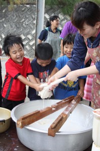 臼で引いた大豆を木綿の袋でこす子どもたち＝１日、城辺社会福祉センター