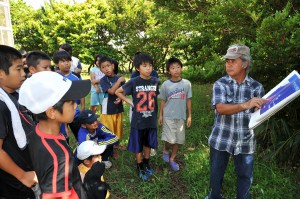 佐渡山さん（右）からツマグロゼミの分布などの説明を聞く子どもたち＝23日、上野ツマグロゼミ増殖施設