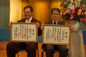 下地さん（右）と新城さんに山之口貘賞の賞状と記念品が贈られた＝７月29日、那覇市、琉球新報ホール