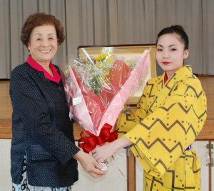 狩俣さんから與那覇さん（左）に花束が贈呈された＝９日、荷川取公民館
