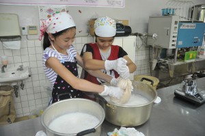 豆乳とおからに分ける工程に挑戦する子どもたち＝９日、ＪＡおきなわ宮古地区本部加工室
