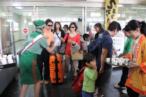 ス宮古らからマンゴージュースを受け取る観光客たち＝１日、宮古空港到着ロビー