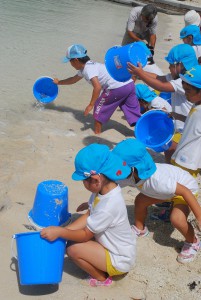 タマンの稚魚を放流する子どもたち＝19日、平良のトゥリバー海岸