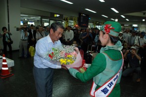 初便で到着した高谷組合長（左）にミス宮古から花束が贈呈された＝28日、宮古空港