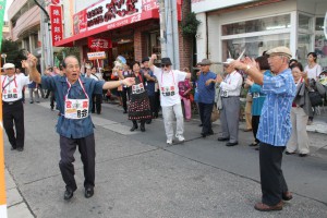 パレードの途中でクイチャーを踊り出す沖縄郷友会のメンバー＝西里通り