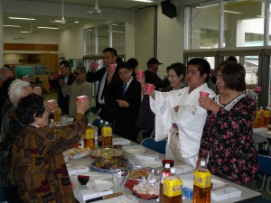 仲宗根大介さん（右から２人目）の成人を祝い乾杯する関係者＝20日、狩俣集落センター