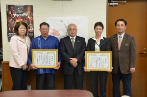 下地市長（中央）から厚生労働大臣感謝状の伝達を受けた松川さん（左から２人目）と下地さん（同４人目）＝２３日、市役所平良庁舎