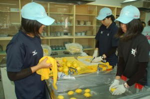 商工会議所と高校生たち約100人で構成する食料部は早朝5時から始動。ボランティアの人たちの弁当7000食を 現場に届けた。写真は、選手たちが食べやすいようにと果物を水洗いし一口サイズに切る女性たち
