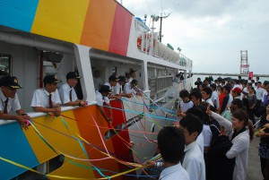 実習生（左）らは、家族や友人らの五色テープに見送られた＝２０日、平良港