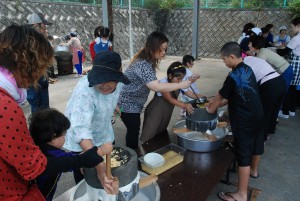 子どもたちはゆでた大豆をひき臼で回し大豆汁を外に送り出した＝３日、市社会福祉センター