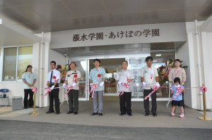 テープカットを行う（左から）浜川さん、長濱副市長、里村参事、花城理事長、仲間園長、親里さん＝６日、漲水学園・あけぼの学園