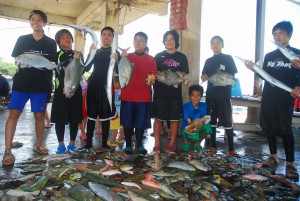 ガーラなどを手に大漁を喜ぶ生徒たち＝１１日、狩俣漁港