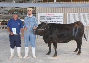 １００日肥育コンテストで優勝した大海の上地良淳さん（左）と上地真誠さん。牛は「としこ」号＝５日、ＪＡおきなわ宮古家畜市場