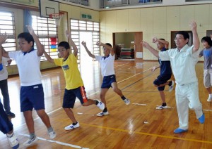 うるかクイチャーを練習する子どもたち。右は講師の宮里和芳さん＝２４日、砂川小体育館