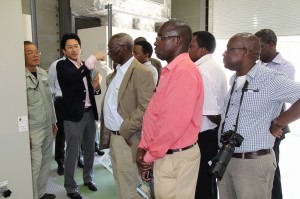 模擬配電系統設備を見学するケニア視察団のメンバーたち＝１５日、メガソーラー実証研究設備