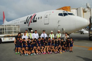飛行機をバックに記念撮影する子どもたちと関係者ら＝２２日、宮古空港