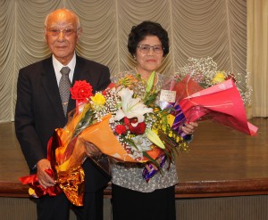 教え子たちから花束を贈呈された根間仙雅さんと妻の貞子さん＝１１月３０日、ホテル共和