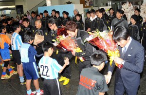 少年サッカーチームの代表選手が（右から）山口監督、シュナイダー潤之介主将、三浦知良選手らに花束を贈呈した＝24日、宮古空港