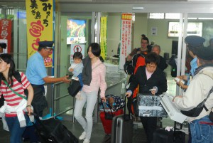 観光客らに広報用ティッシュを配布する平良所長（左）ら＝23日、宮古空港