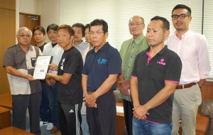 大会長の下地市長（左）に高木さん（同２人目）が地元選手の出場枠拡大の要請書を手渡した＝30日、平良庁舎応接室