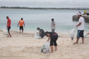 砂浜に打ち上げられた漂流物を拾い集める参加者＝16日、来間漁港