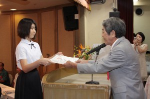児童・生徒の部で大賞に選ばれた平良智香さんに書心会の天久宏会長から賞状が手渡された＝25日、ホテル共和