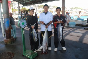 大物カツオや大物マグロを手に喜ぶ生徒たち＝31日、佐良浜漁港