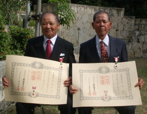 秋の叙勲伝達式に出席し勲章勲記を手にした川平さん（右）と松原さん＝７日、県知事公舎中庭