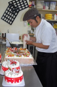 クリスマスのケーキ作りに追われる菓子店の厨房＝23日、市内平良のケーキ店