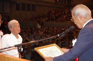老人クラブ育成功労者として友利さん（左）らが上里連合会長から表彰状を手渡された＝15日、マティダ市民劇場