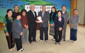 垣花会長（中央左）が砂川会長に伝達した＝26日、市社会福祉協議会