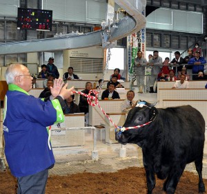 １番牛に80万１０００円（左上電光掲示板）の高値が付き初競りの市場は大歓声に包まれた＝19日、ＪＡおきなわ宮古家畜市場