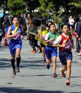 沿道の声援を受けながら力走する女子児童。力の限りを尽くした＝２２日、市陸上競技場周辺