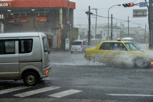 激しい雨の影響で道路に水がたまり、車は水しぶきを上げて走行していた＝２７日午前１０時５０分すぎ、北給油所前交差点