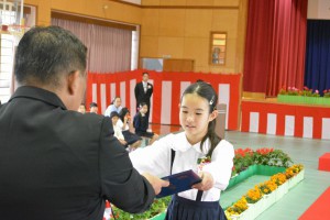 国仲校長（左）から卒業証書を受け取る砂川さん＝19日、宮原小体育館