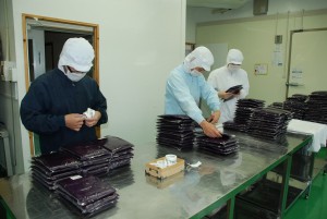 袋詰めにした紫イモのペーストにラベルを貼る職員たち＝２４日、市いも加工施設
