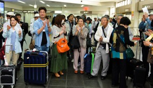 セレモニーで三線と歌を披露した瀬名波さんと川満さんに拍手する観光客ら＝２７日、宮古空港
