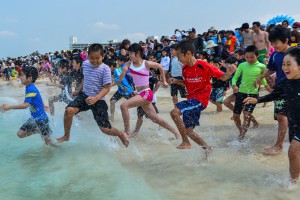 ボランティアの合図で一斉に海に入る参加者ら＝６日、与那覇前浜ビーチ