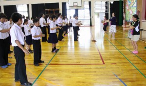 マウイ島から来た３人の高校教師（右）の動きを見ながらフラダンスに挑戦する生徒たち＝１６日、城辺中学校体育館