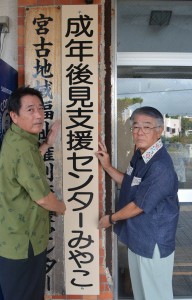 垣花会長（右）と下地事務局長が看板を掲げた＝１０日、市社協